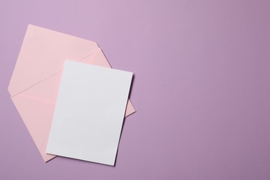 Photo of Letter envelope and card on violet background, top view. Space for text