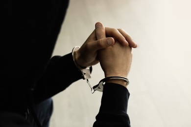 Man detained in handcuffs indoors, closeup view. Criminal law