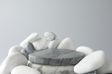 Photo of Presentation for product. Stone podium and pebbles on light grey background. Space for text