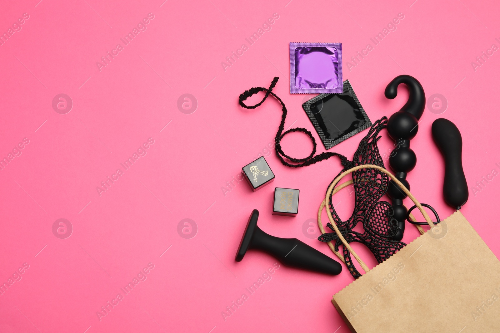 Photo of Shopping bag and different sex toys on pink background, flat lay. Space for text