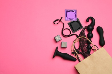 Photo of Shopping bag and different sex toys on pink background, flat lay. Space for text