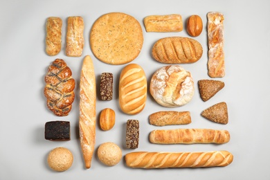 Photo of Different kinds of fresh bread on light background, flat lay