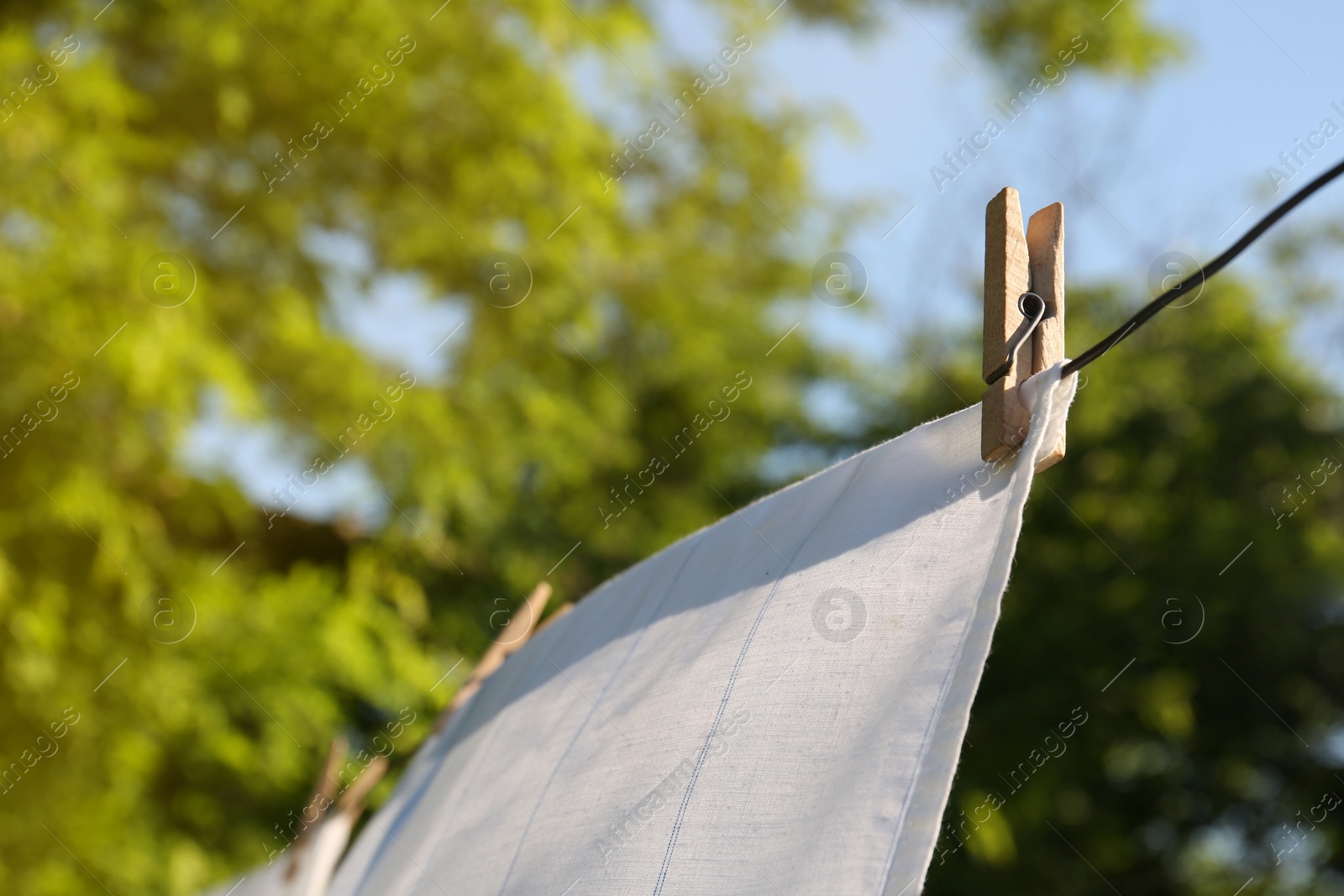 Photo of Washing line with clean laundry and clothespins outdoors, closeup