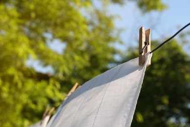 Washing line with clean laundry and clothespins outdoors, closeup