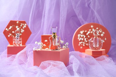 Photo of Stylish presentationperfume bottles and gypsophila flowers on light violet fabric