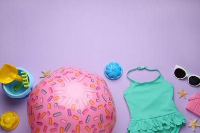 Flat lay composition with pink beach ball and sand toys on violet background. Space for text