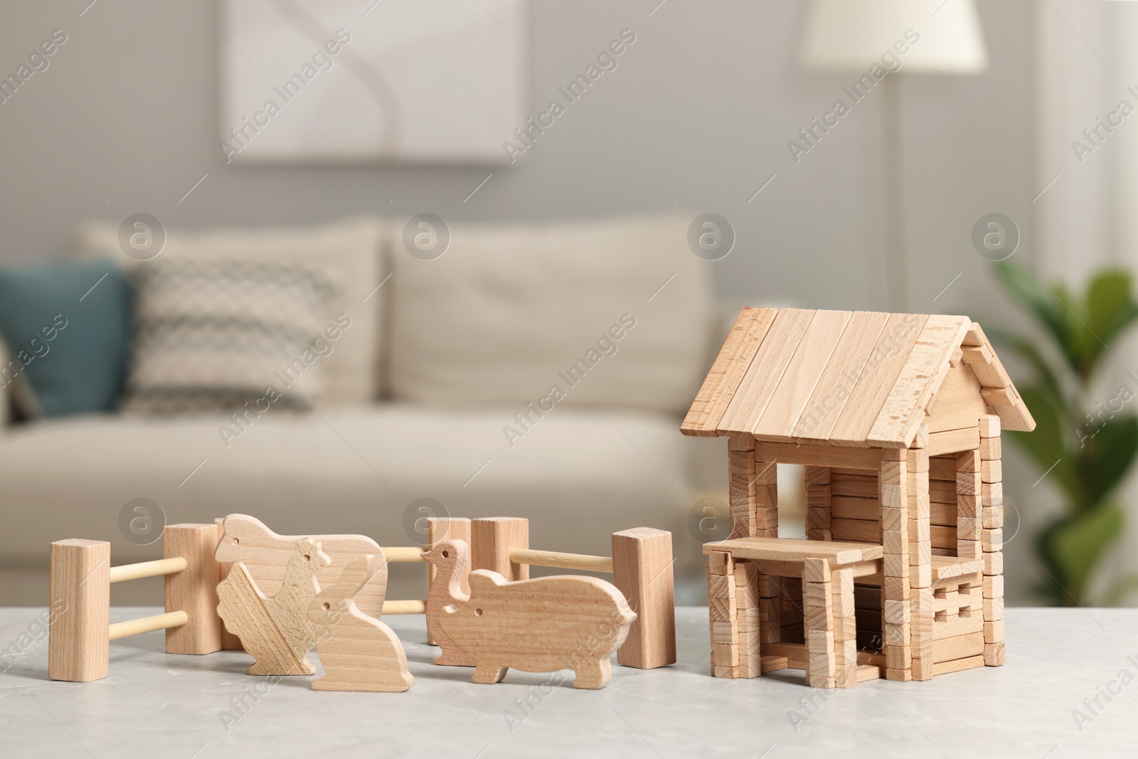 Photo of Wooden house, animals and fence on light grey table indoors. Children's toys