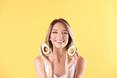 Portrait of young beautiful woman with ripe delicious avocado on color background