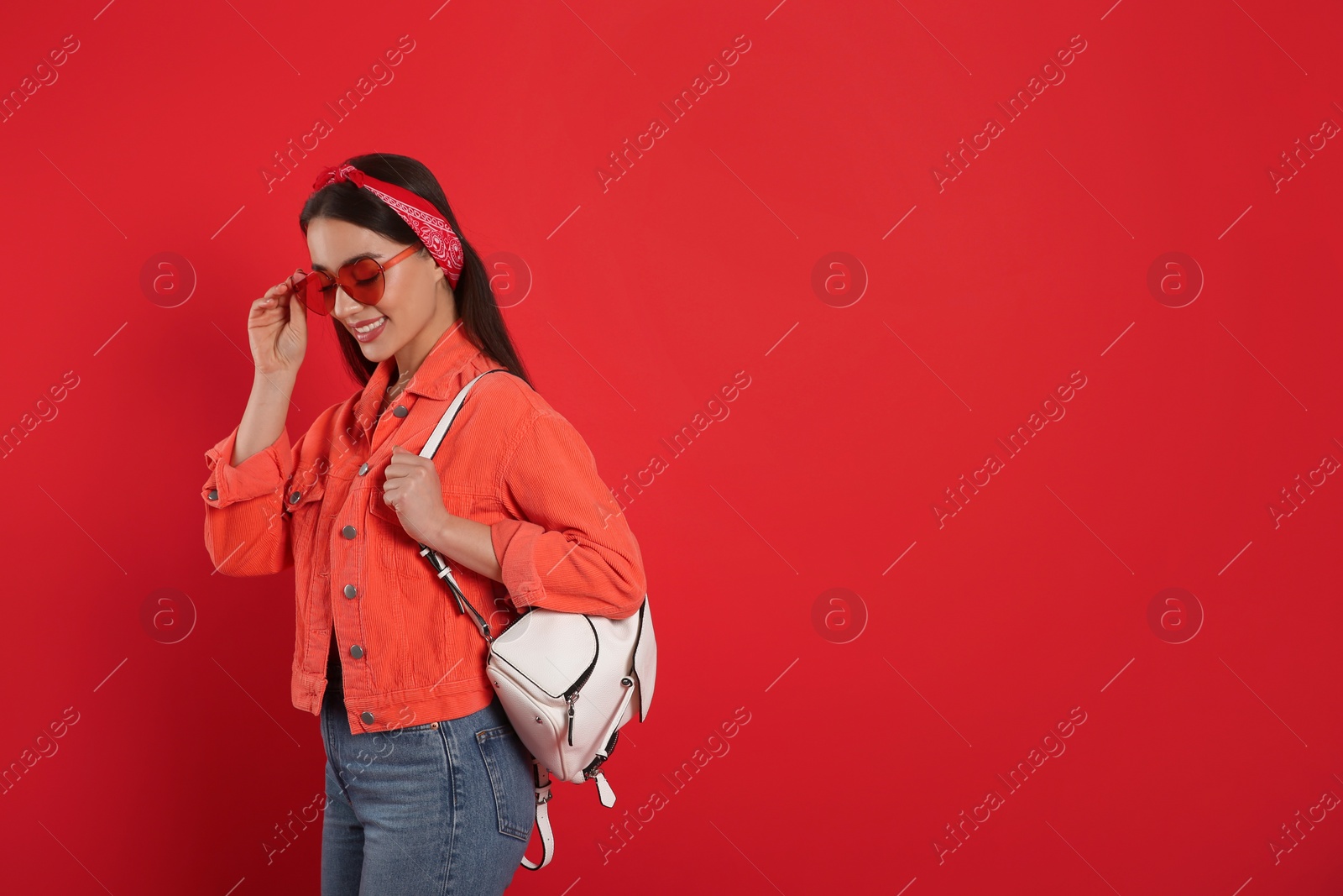 Photo of Beautiful young woman with stylish leather backpack on red background. Space for text