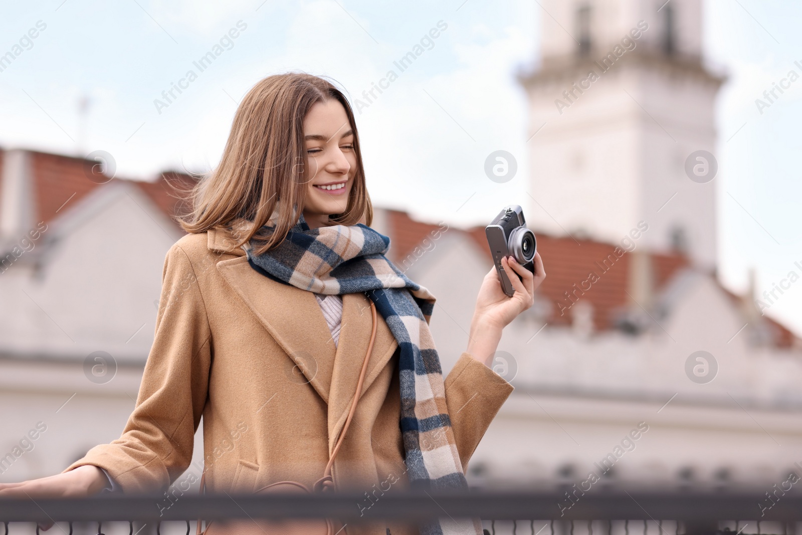 Photo of Beautiful woman in warm scarf with vintage camera outdoors