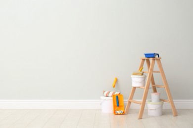 Photo of Decorator's kit of tools and paints near light wall indoors. Space for text