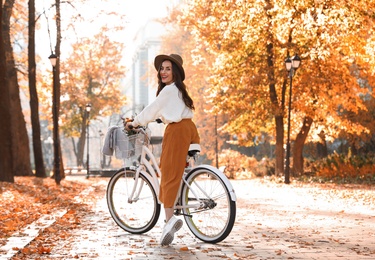 Beautiful happy woman riding bicycle in autumn park