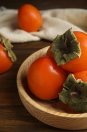 Photo of Tasty ripe persimmons on wooden table, closeup