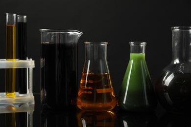 Photo of Laboratory glassware with different types of oil on black background