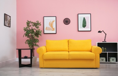 Photo of Modern living room interior with comfortable yellow sofa near color wall