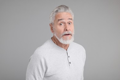Photo of Portrait of surprised senior man on grey background