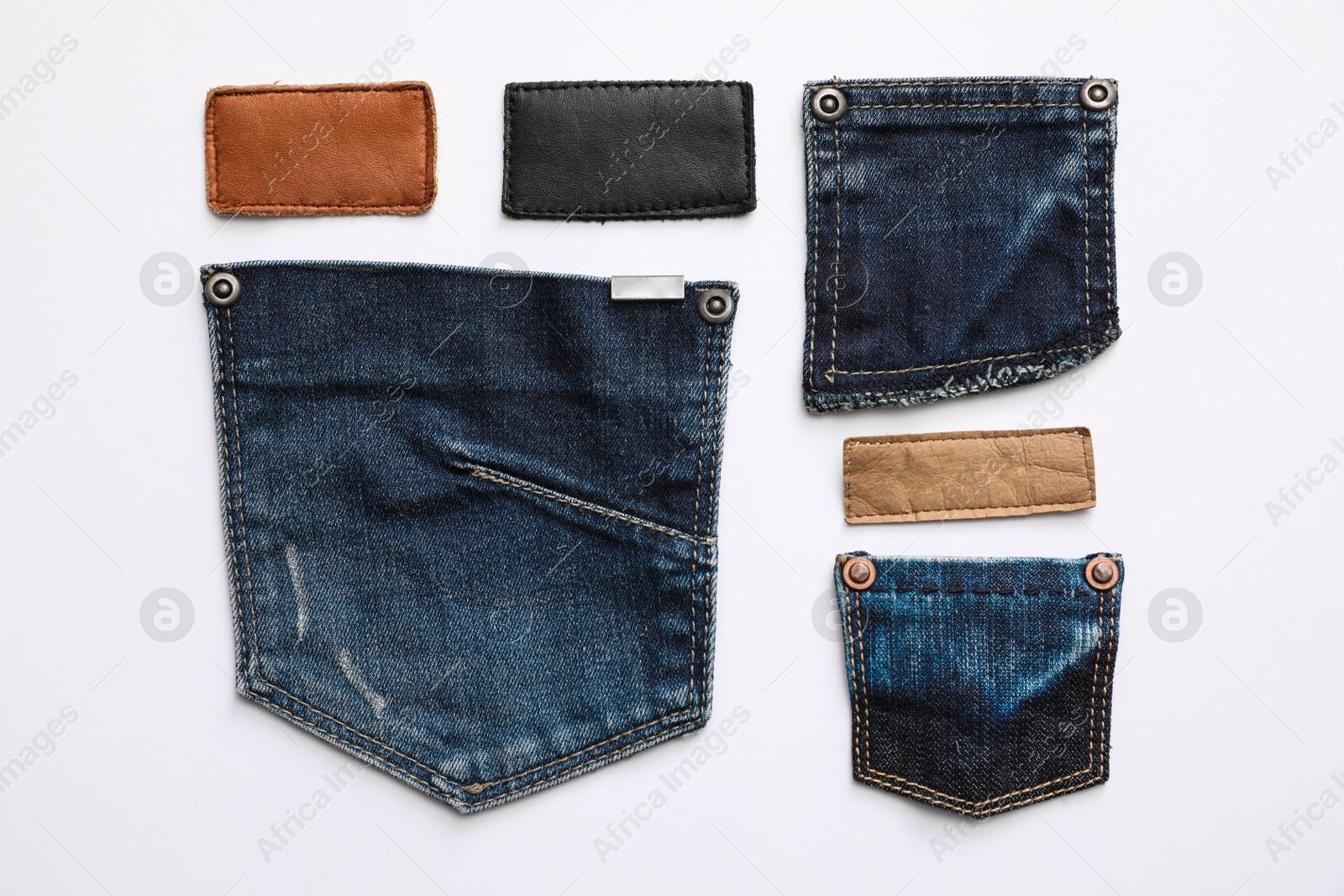 Photo of Stylish jeans pockets and labels isolated on white, top view