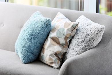 Photo of Different soft pillows on sofa in room. Interior element