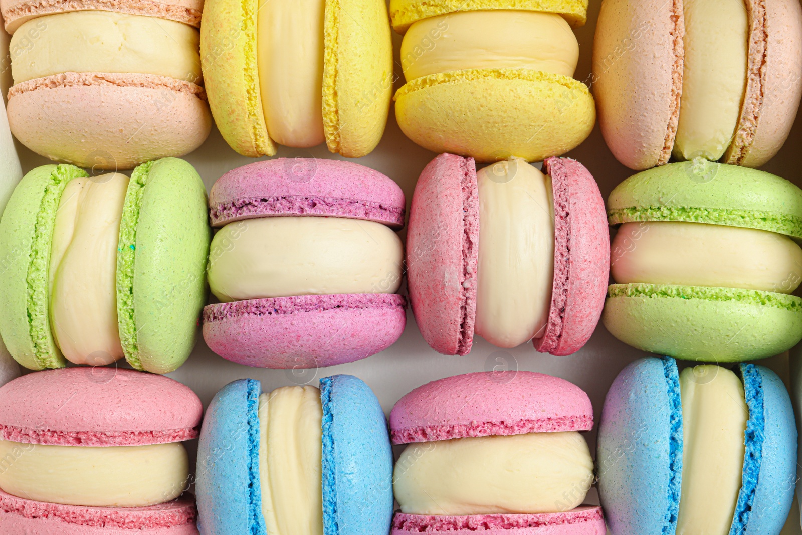 Photo of Many delicious colorful macarons on white background, top view