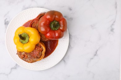 Photo of Delicious stuffed bell peppers served on white marble table, top view. Space for text