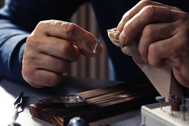 Photo of Professional jeweler working with ring at table, closeup