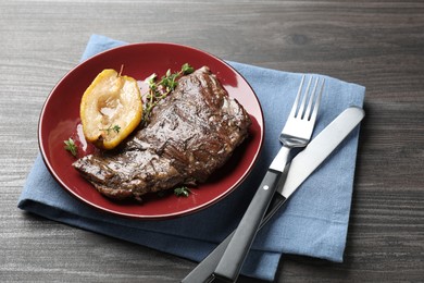 Photo of Delicious roasted beef meat, caramelized pear and thyme served on grey wooden table