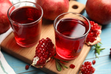 Photo of Pomegranate juice and fresh fruits on light blue wooden table