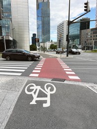 Photo of Bicycle lane with white sign painted and pedestrian crossing on asphalt road