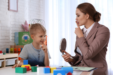 Photo of Speech therapist working with little boy in office