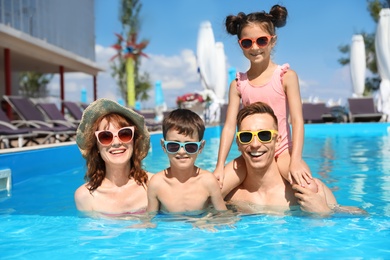 Photo of Happy family in swimming pool at resort