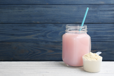 Photo of Protein shake and powder on white wooden table, space for text