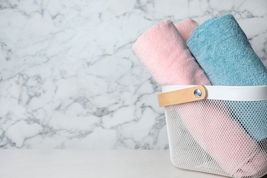 Photo of Basket with soft bath towels on table. Space for text