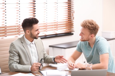 Photo of Insurance agent consulting young man in office