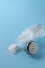 Photo of Organic white salt in shaker on light blue background