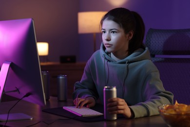 Photo of Girl with energy drink playing computer game at table in room