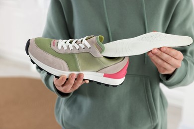 Photo of Woman putting orthopedic insole into shoe indoors, closeup. Foot care