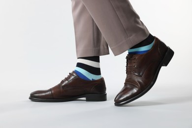 Photo of Man in stylish colorful socks, shoes and pants on white background, closeup