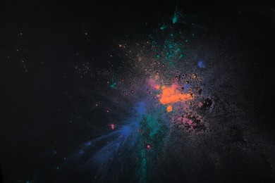 Photo of Colorful powder dyes on dark background, top view. Holi festival