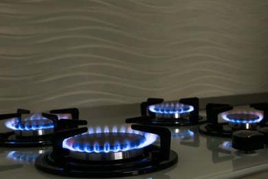 Photo of Modern gas cooktop with burning blue flames in kitchen