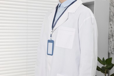 Photo of Doctor with empty badge in hospital, closeup. Space for text