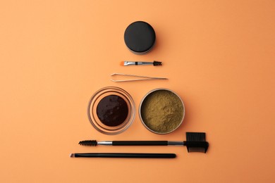 Photo of Flat lay composition with eyebrow henna and professional tools on orange background