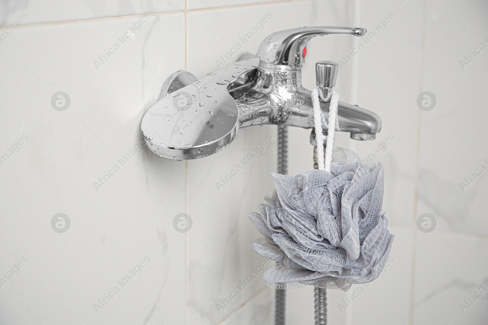 Photo of Grey shower puff hanging on faucet in bathroom