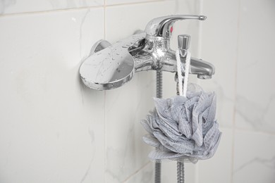 Photo of Grey shower puff hanging on faucet in bathroom