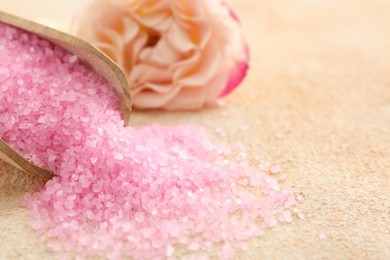 Photo of Pink sea salt and beautiful flowers on color textured table, closeup. Space for text
