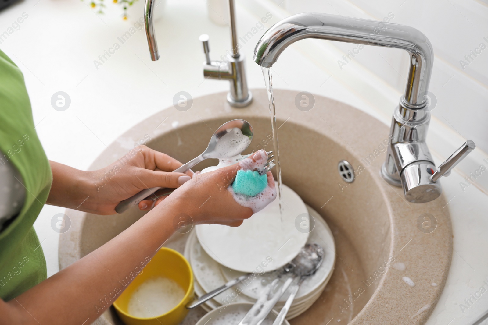 Photo of Woman doing washing up in kitchen sink, closeup view. Cleaning chores