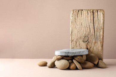 Photo of Presentation for product. Stone podium and pebbles on beige background. Space for text