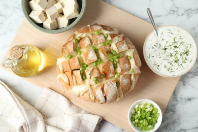 Photo of Freshly baked bread with tofu cheese and green onion served on white marble table, flat lay