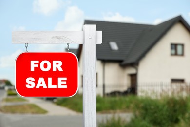 Image of Sale sign near beautiful house outdoors. Red signboard with words