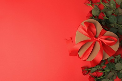 Photo of Heart shaped gift box with bow and beautiful roses on red background, flat lay. Space for text