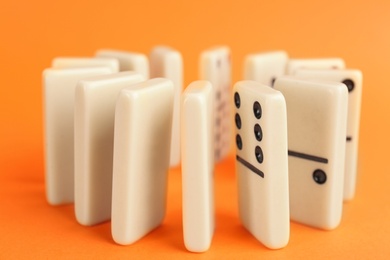 Photo of White domino tiles with black pips on orange background